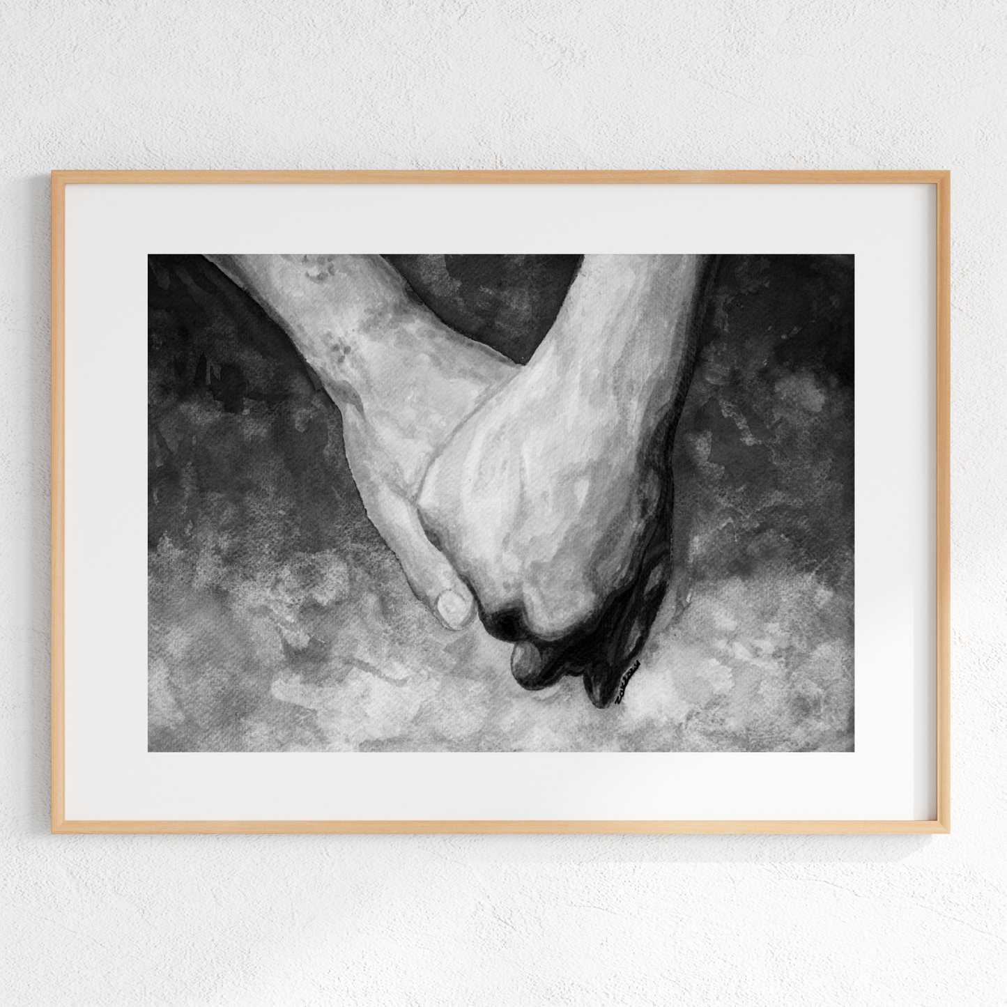 Framed black and white photograph of two hands holding each other on a textured surface.