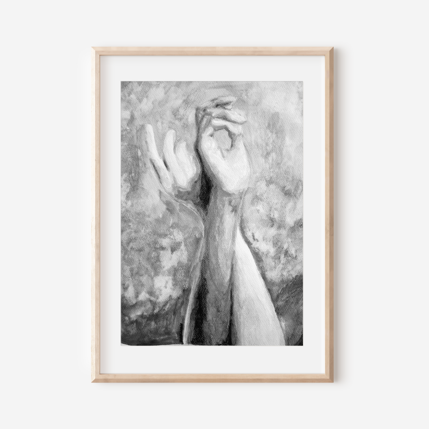 Framed black and white artwork of hands on a white wall