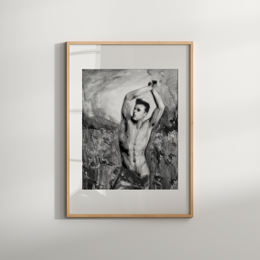 Framed black and white artwork of a nude figure in a natural setting on a light gray wall.