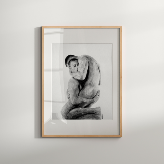 Framed black and white artwork of a nude figure on a light gray wall.