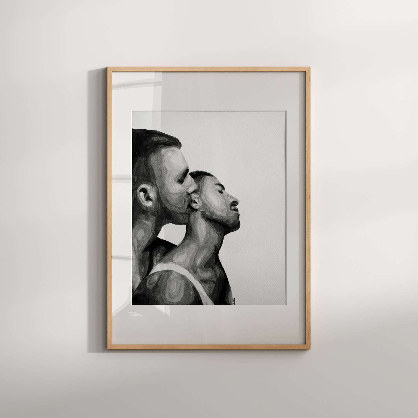 Framed black and white artwork of two men in a close embrace on a white wall.