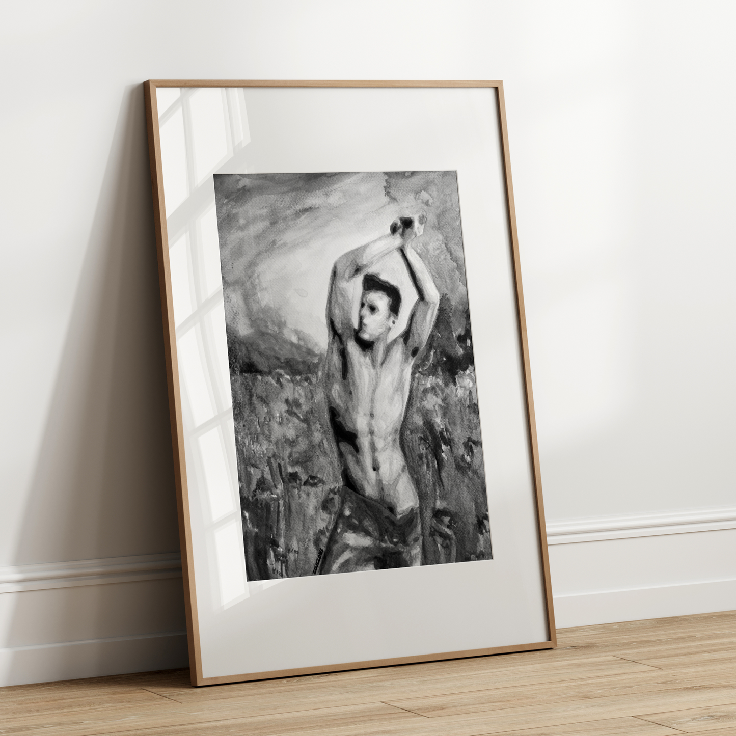 Framed black and white artwork of a nude figure leaning against a rock on a white wall.