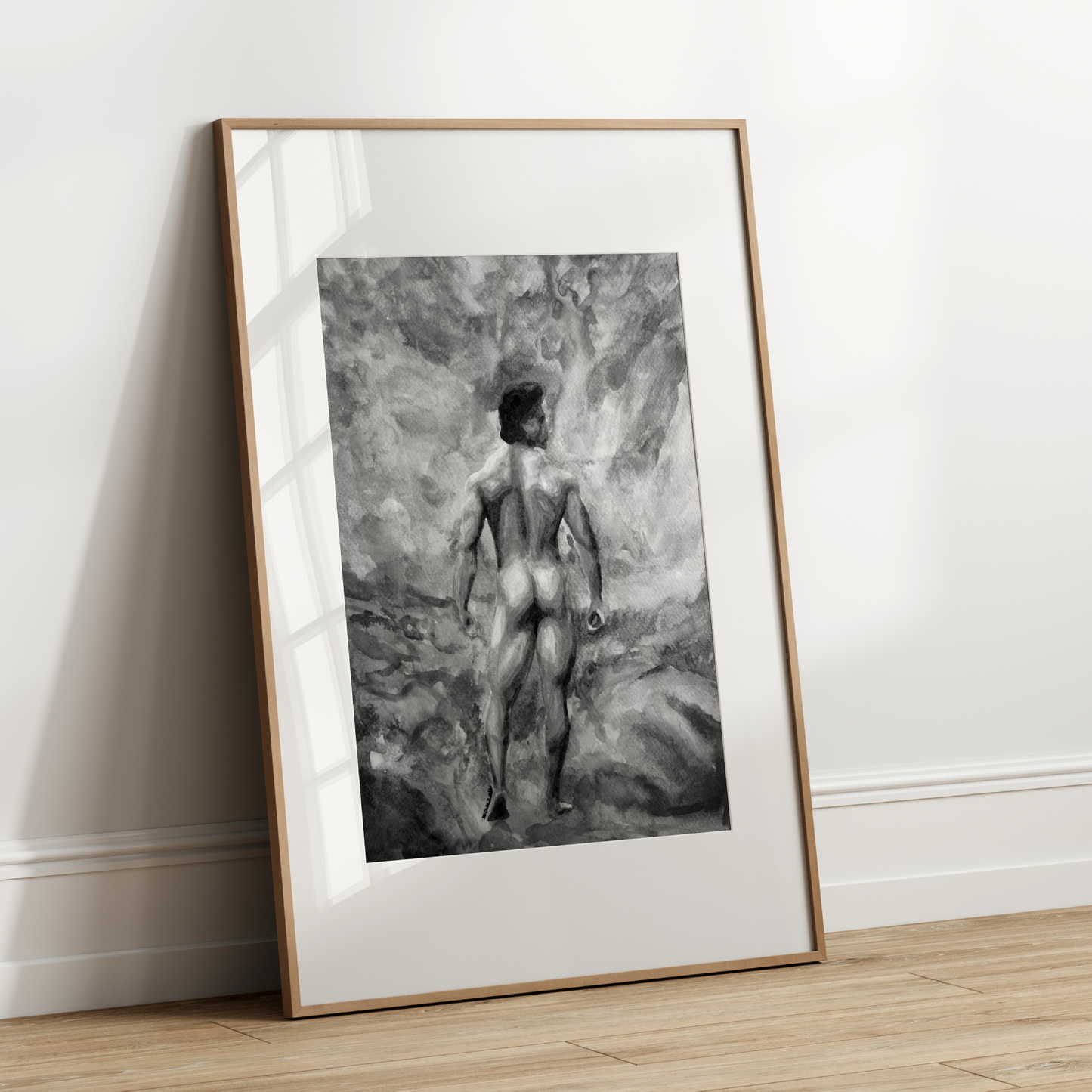 Framed black and white artwork of a nude figure leaning against a textured wall on a wooden floor.