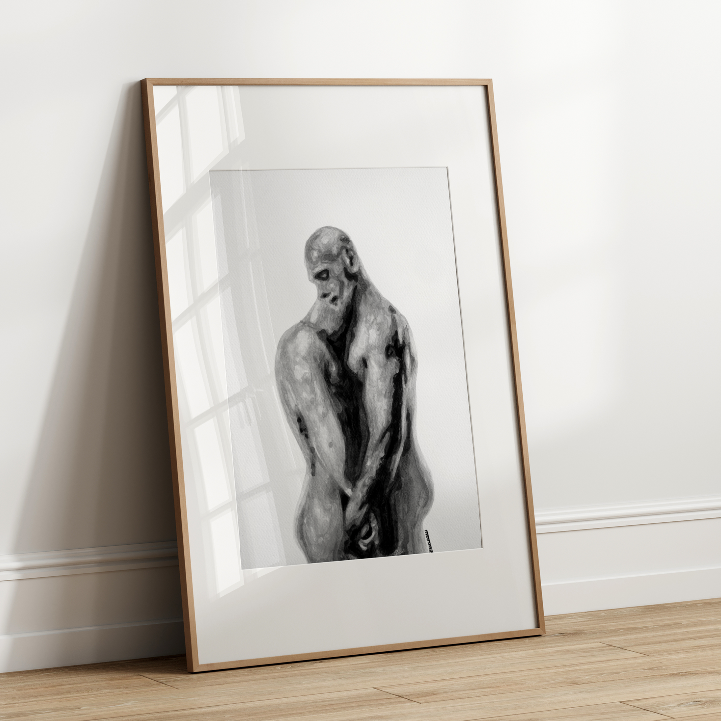 Framed artwork of a nude figure leaning against a white wall.