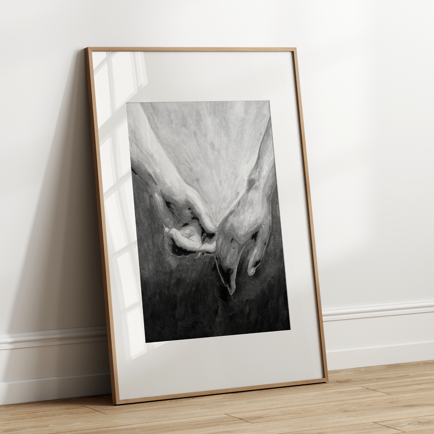 Framed black and white artwork leaning against a white wall.