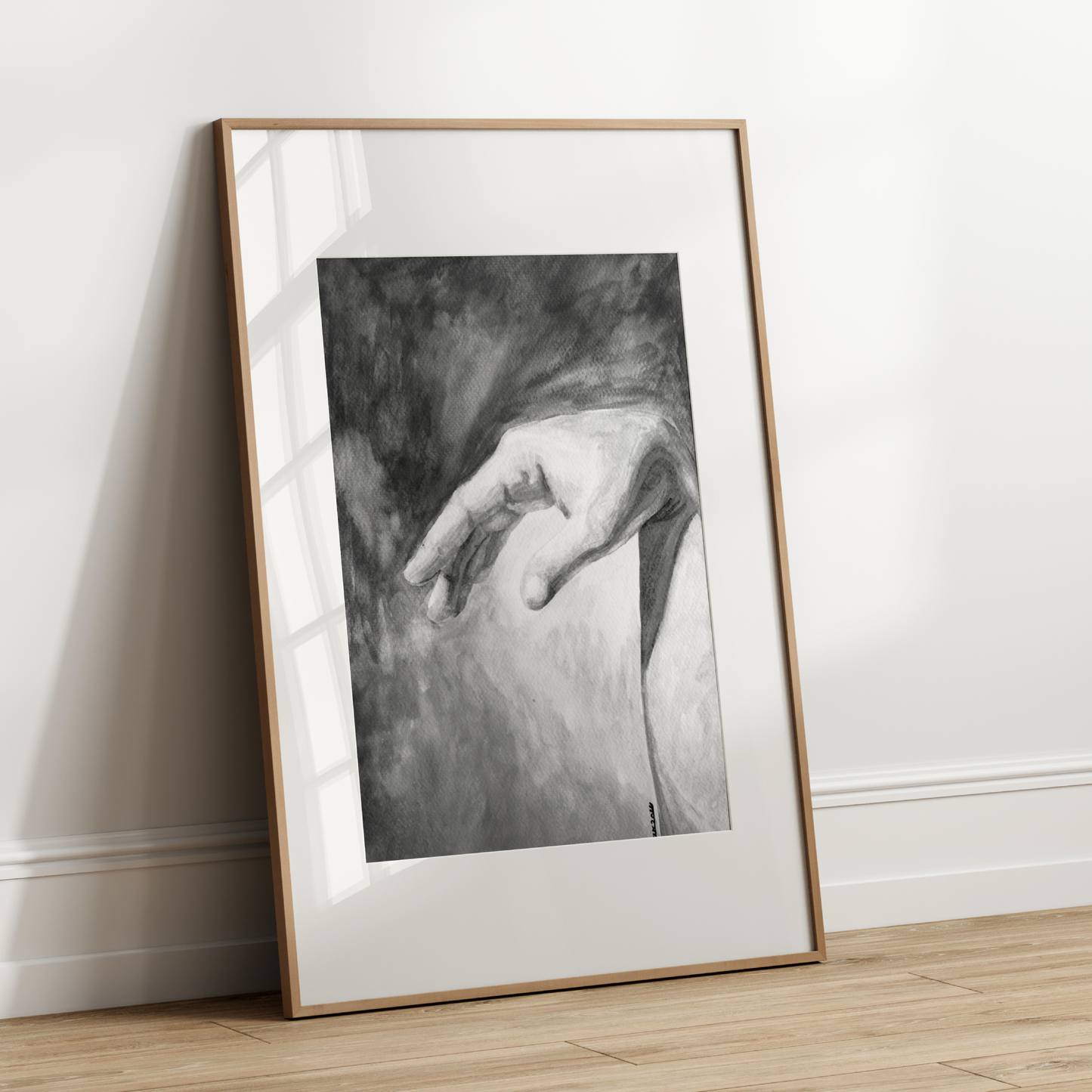 Framed black and white artwork leaning against a white wall.