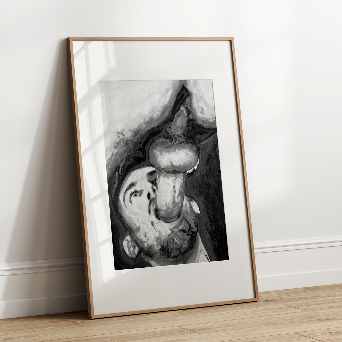 Framed black and white artwork leaning against a white wall.