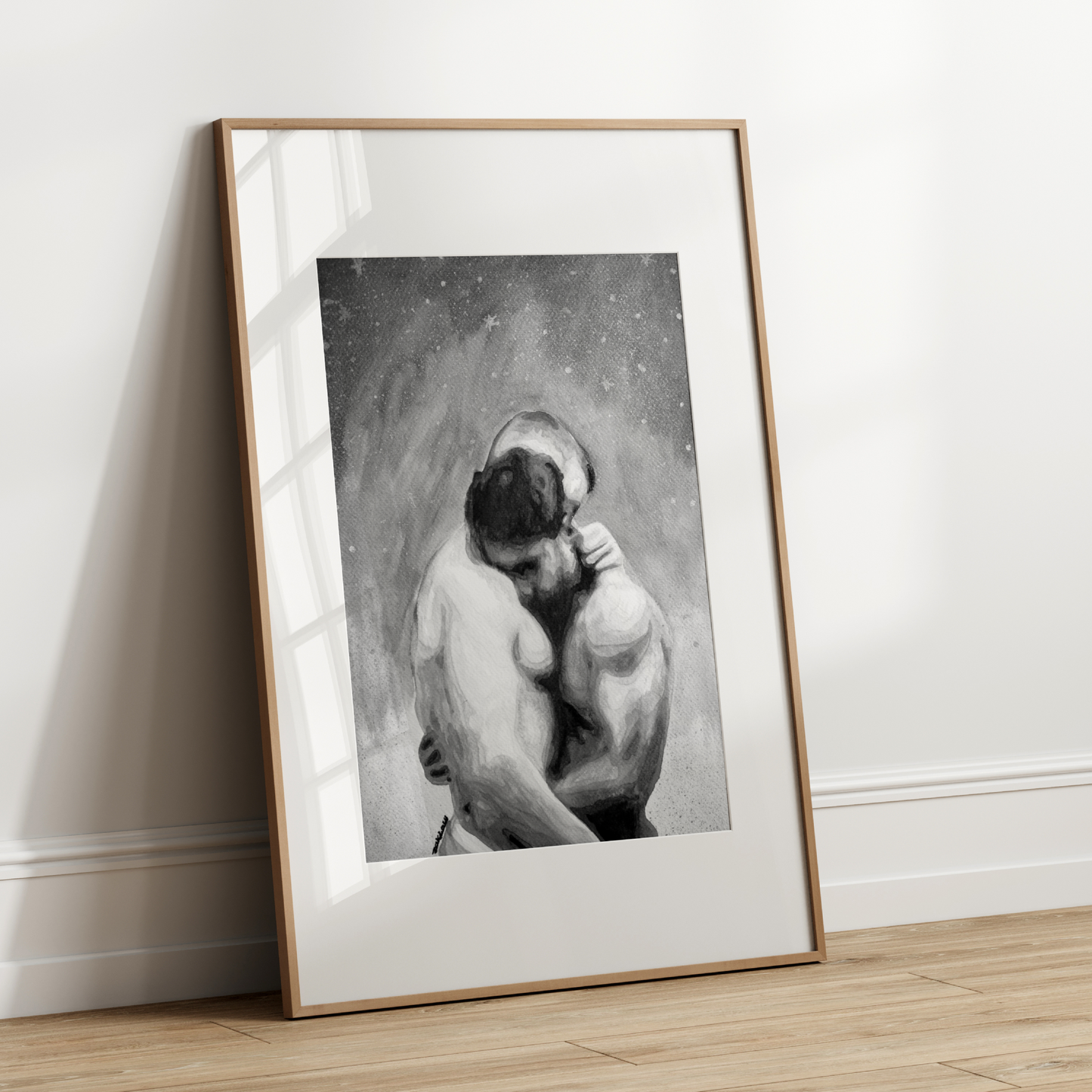 Framed black and white artwork of a nude figure leaning against a wall on a wooden floor.