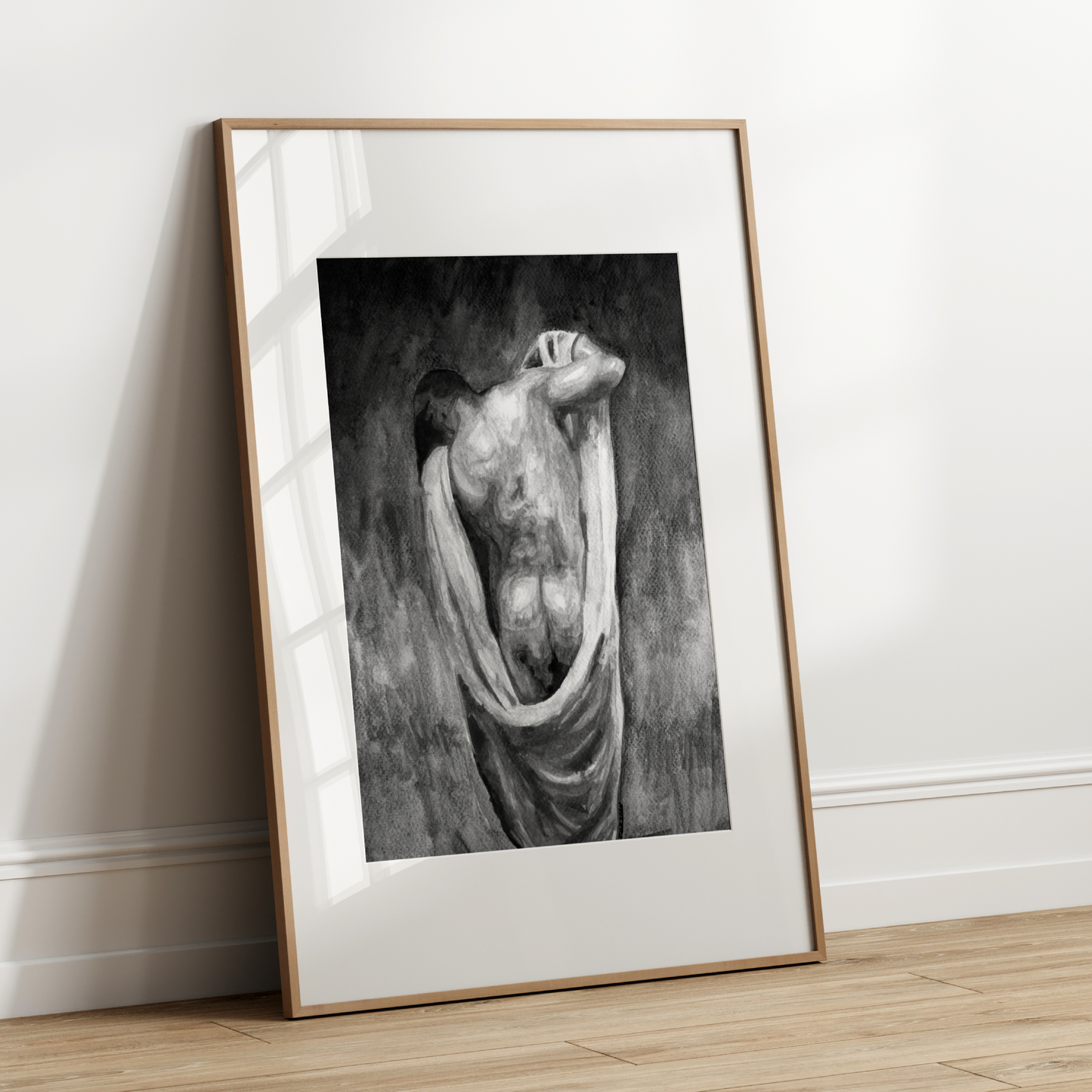 Framed black and white artwork leaning against a white wall.