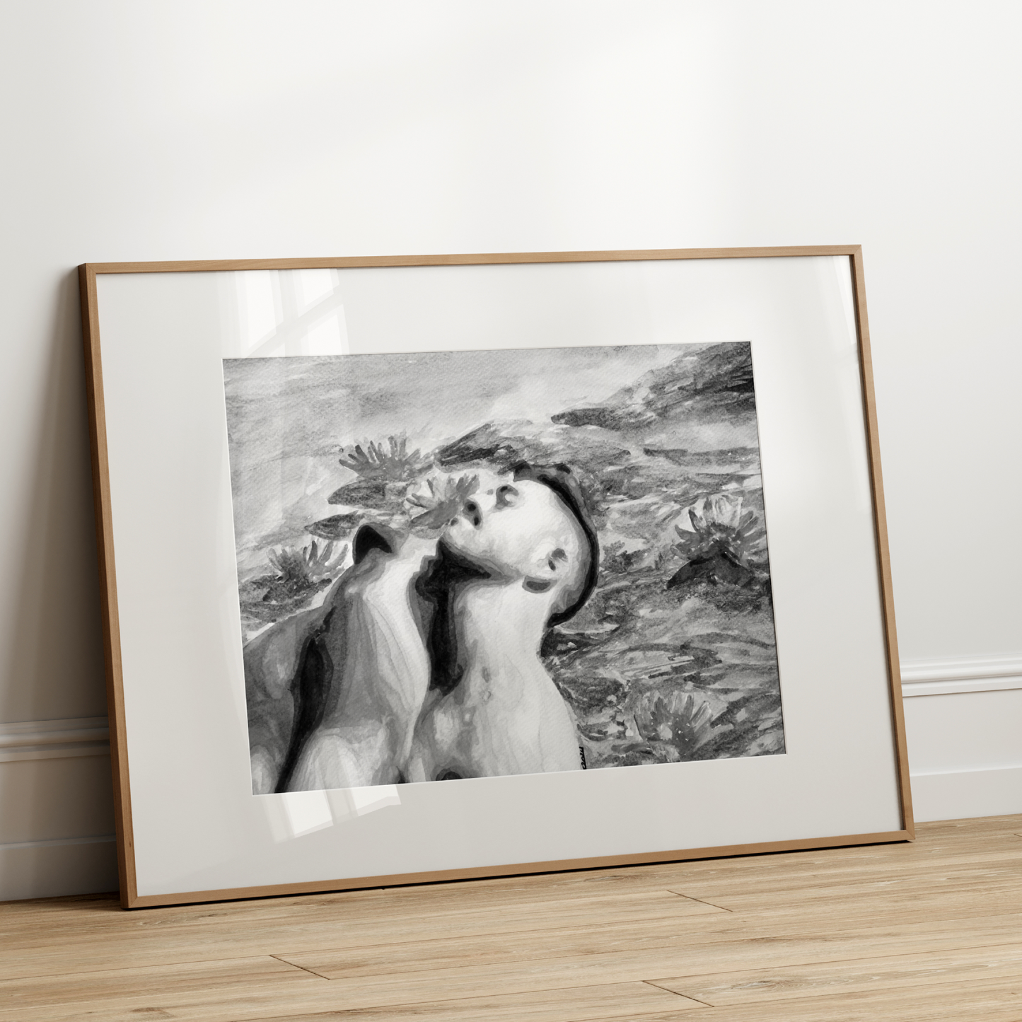 Framed black and white artwork on a wooden floor against a white wall