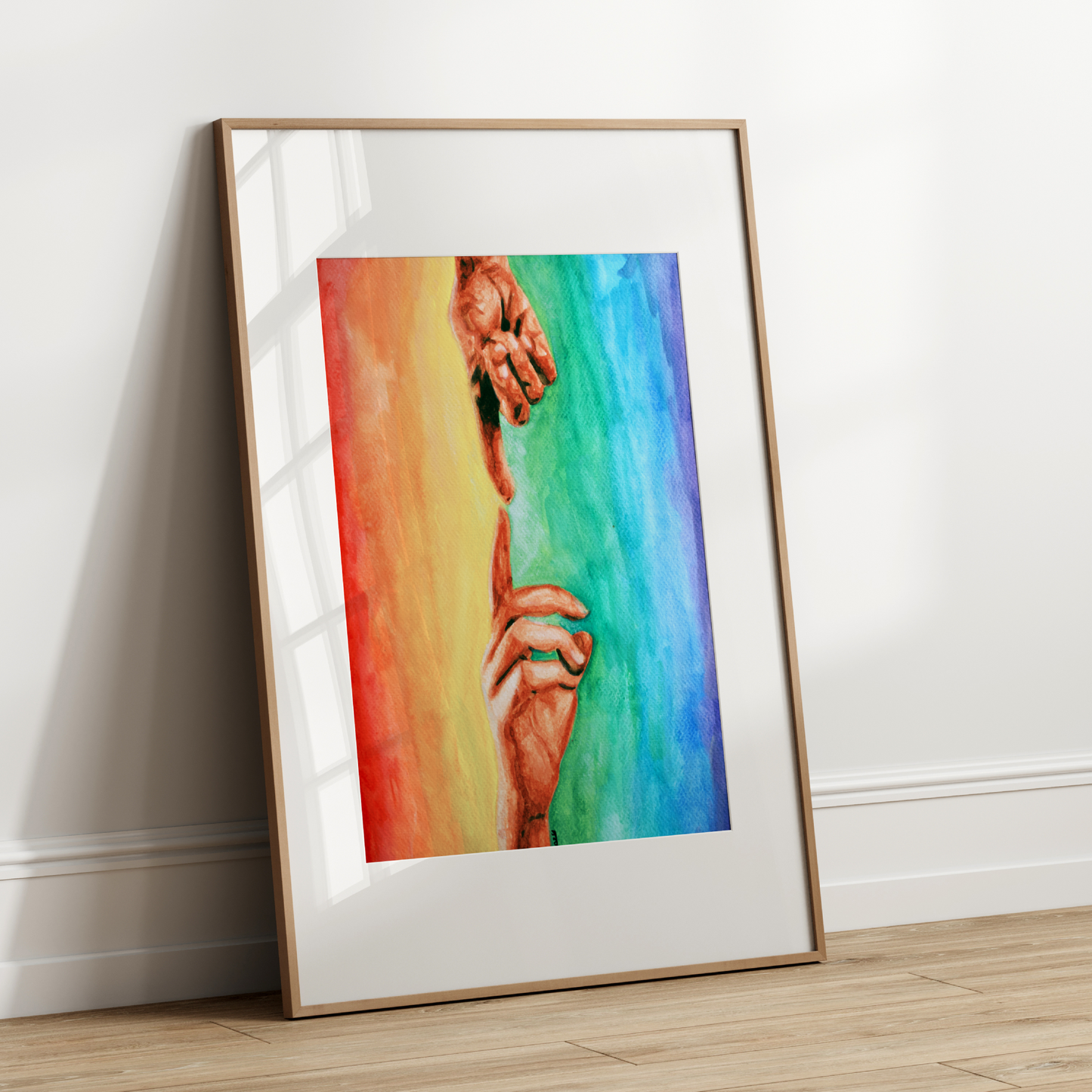 Framed artwork of two hands holding a rainbow-colored heart on a white wall.