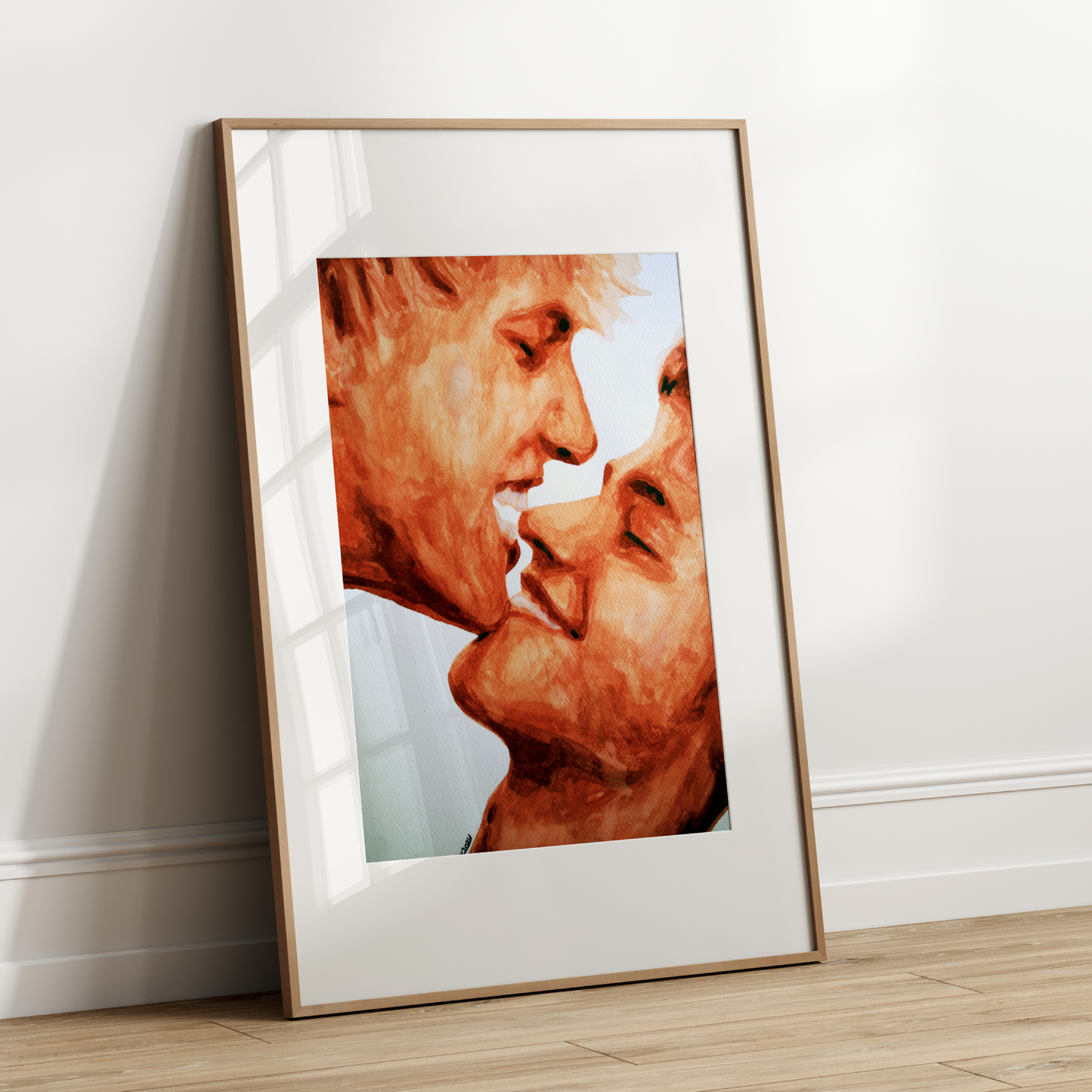 Framed artwork of two faces close together on a white wall.