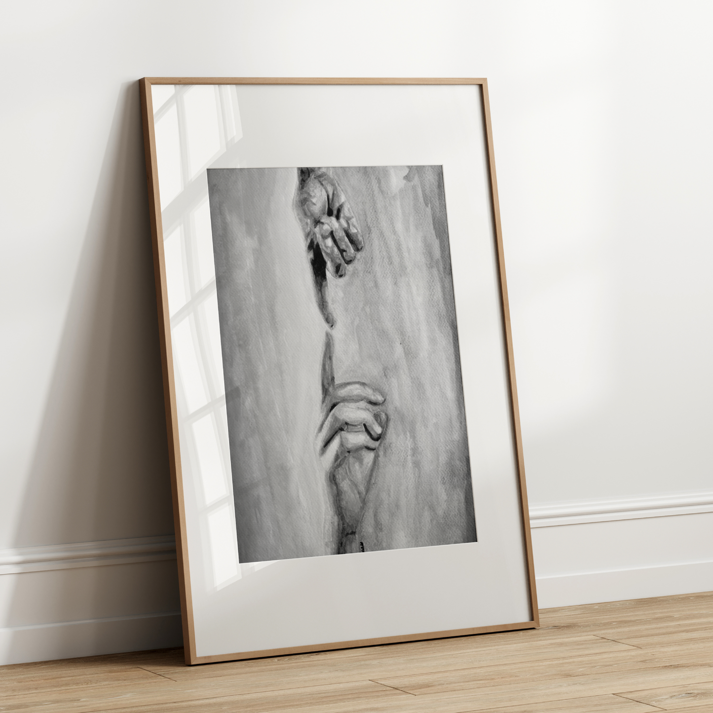 Framed black and white artwork leaning against a white wall.