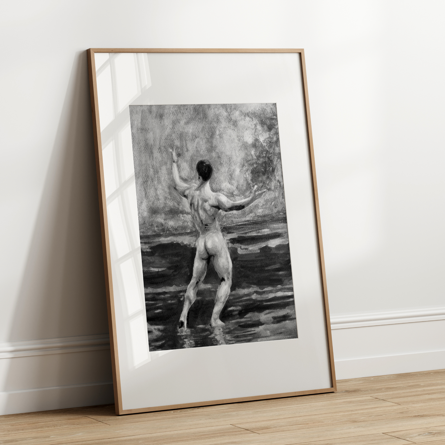 Framed black and white artwork of a nude figure on a white wall.