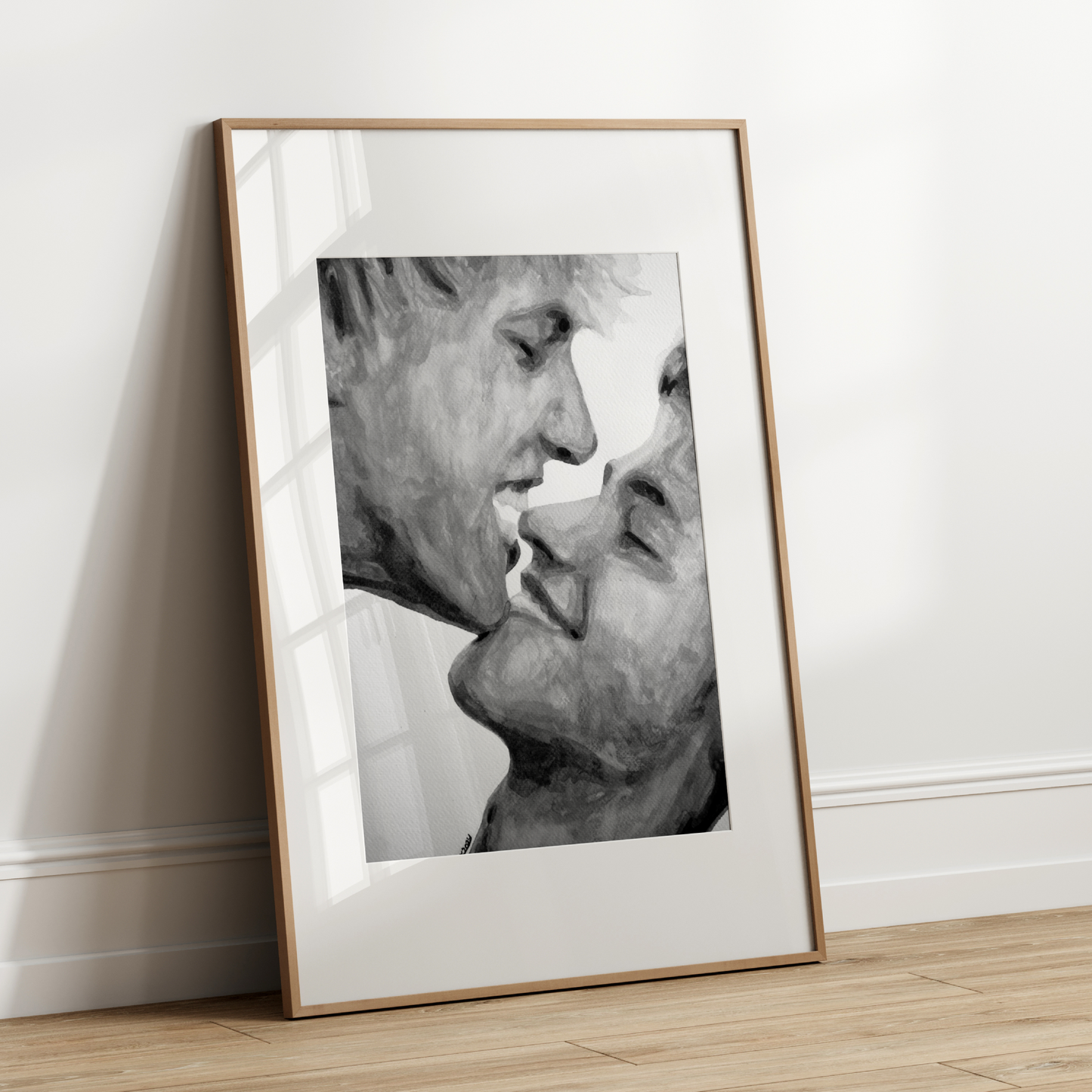 Framed black and white portrait leaning against a white wall.