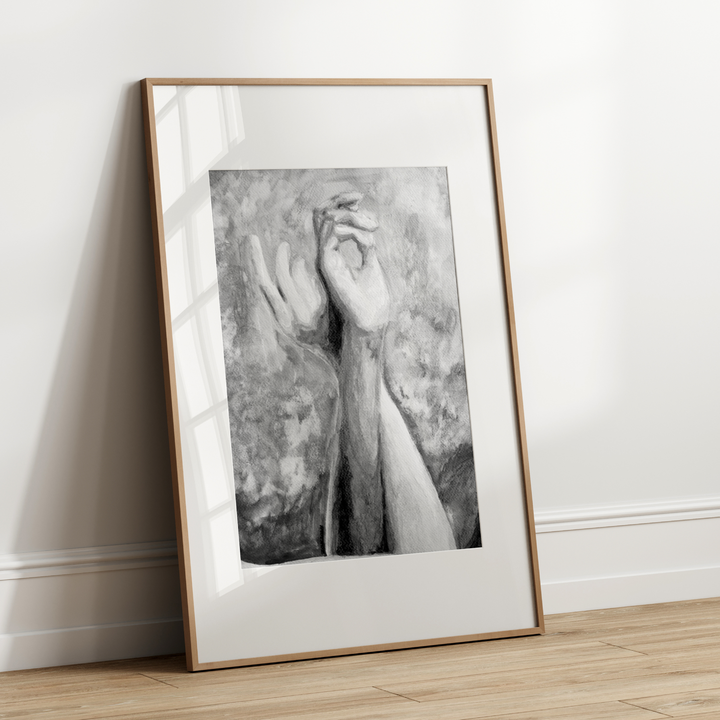 Framed black and white artwork leaning against a white wall.