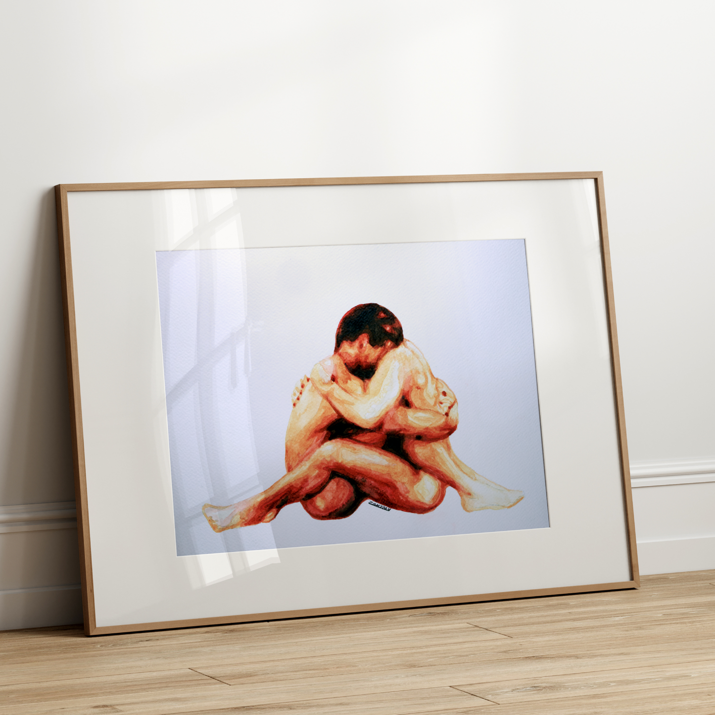 Framed artwork of two people embracing on a white wall.