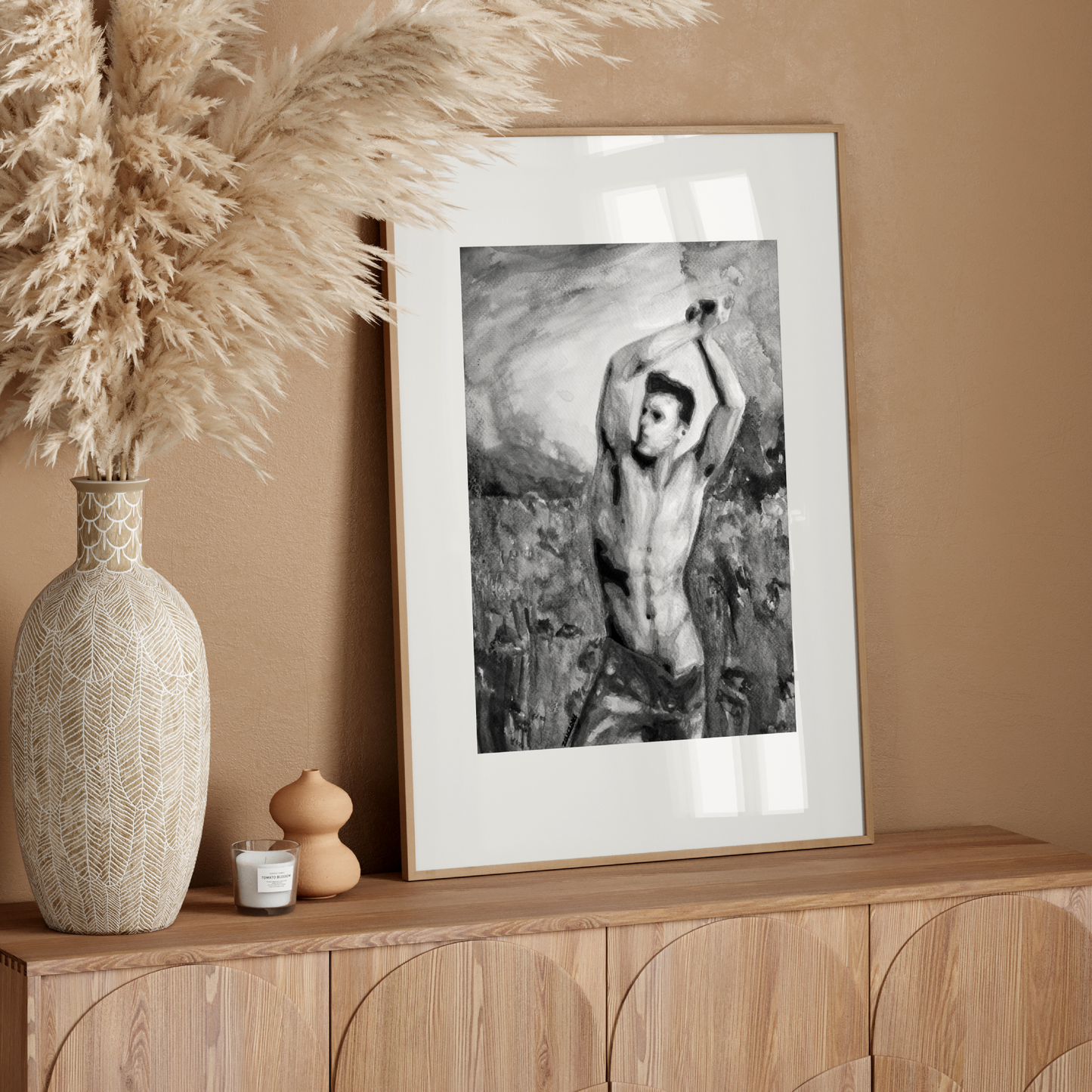 Framed black and white artwork on a wooden sideboard with decorative vase and pampas grass.