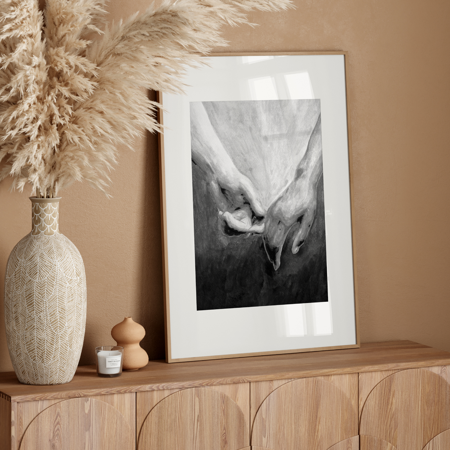 Framed artwork on a wooden console table with decorative elements against a beige wall.