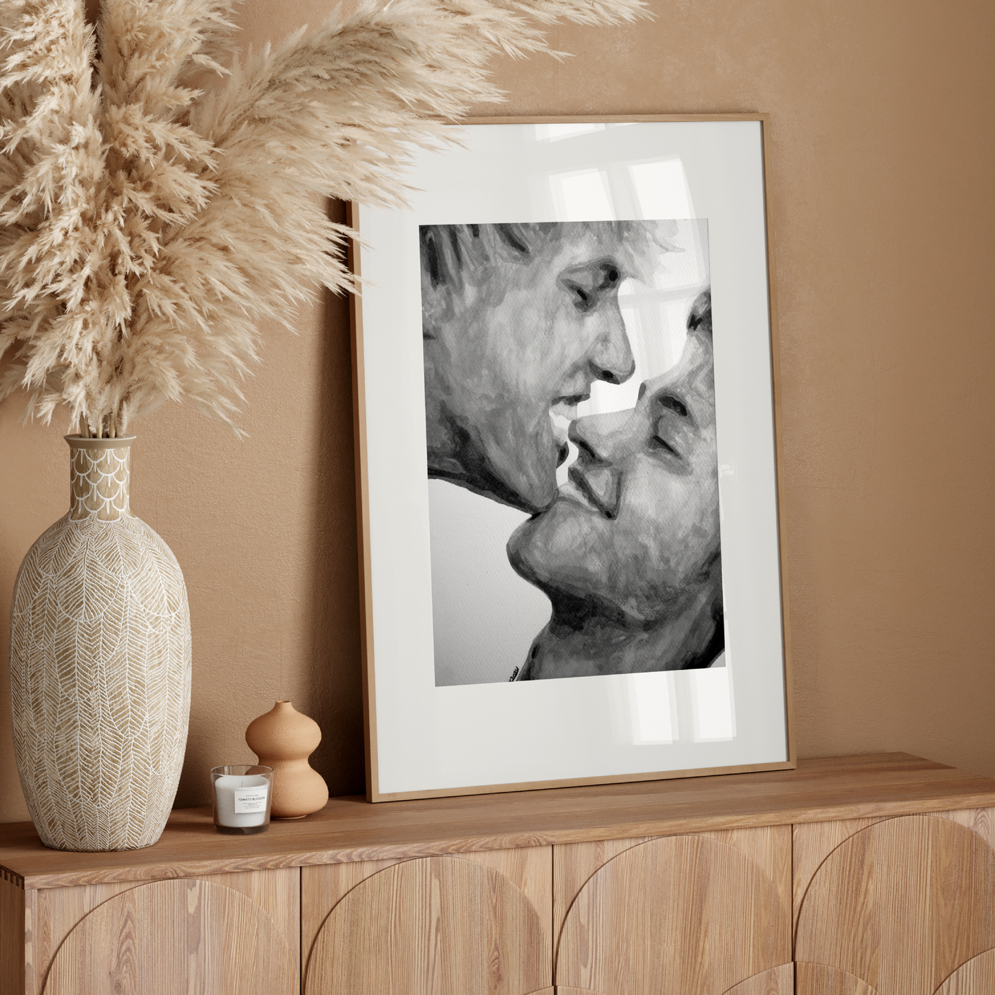 Framed artwork of two people kissing on a wooden sideboard with decorative elements.