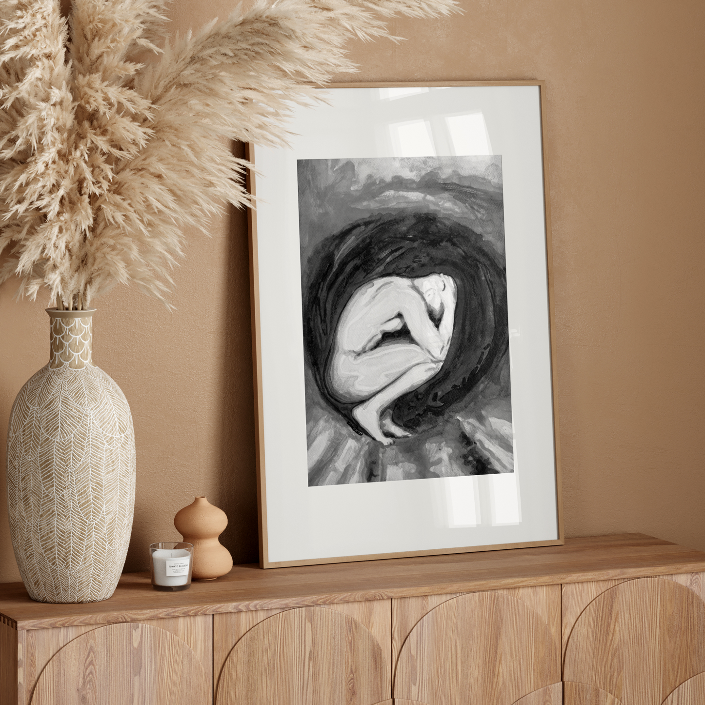 Framed artwork on a wooden console table with decorative elements against a beige wall.