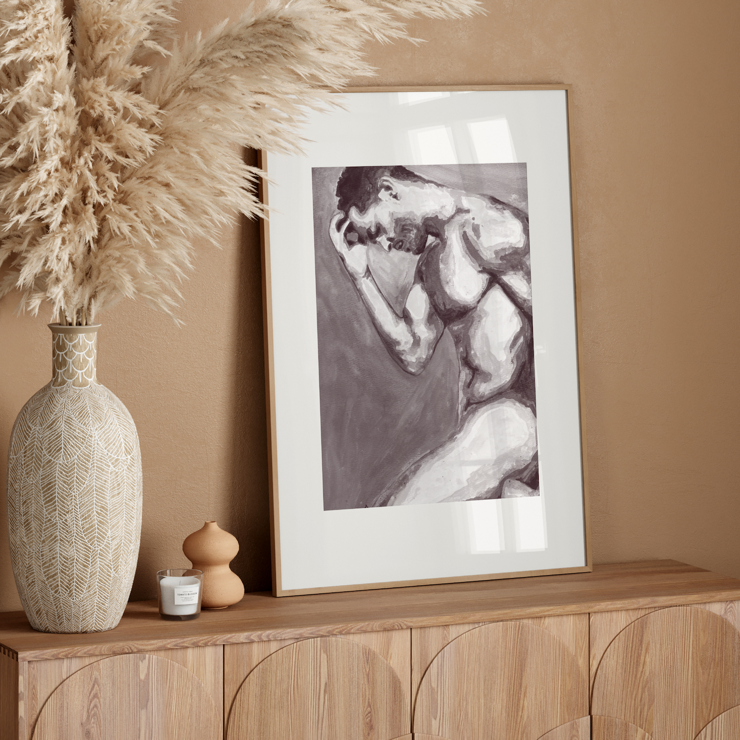 Framed artwork on a wooden console table with decorative elements against a beige wall.