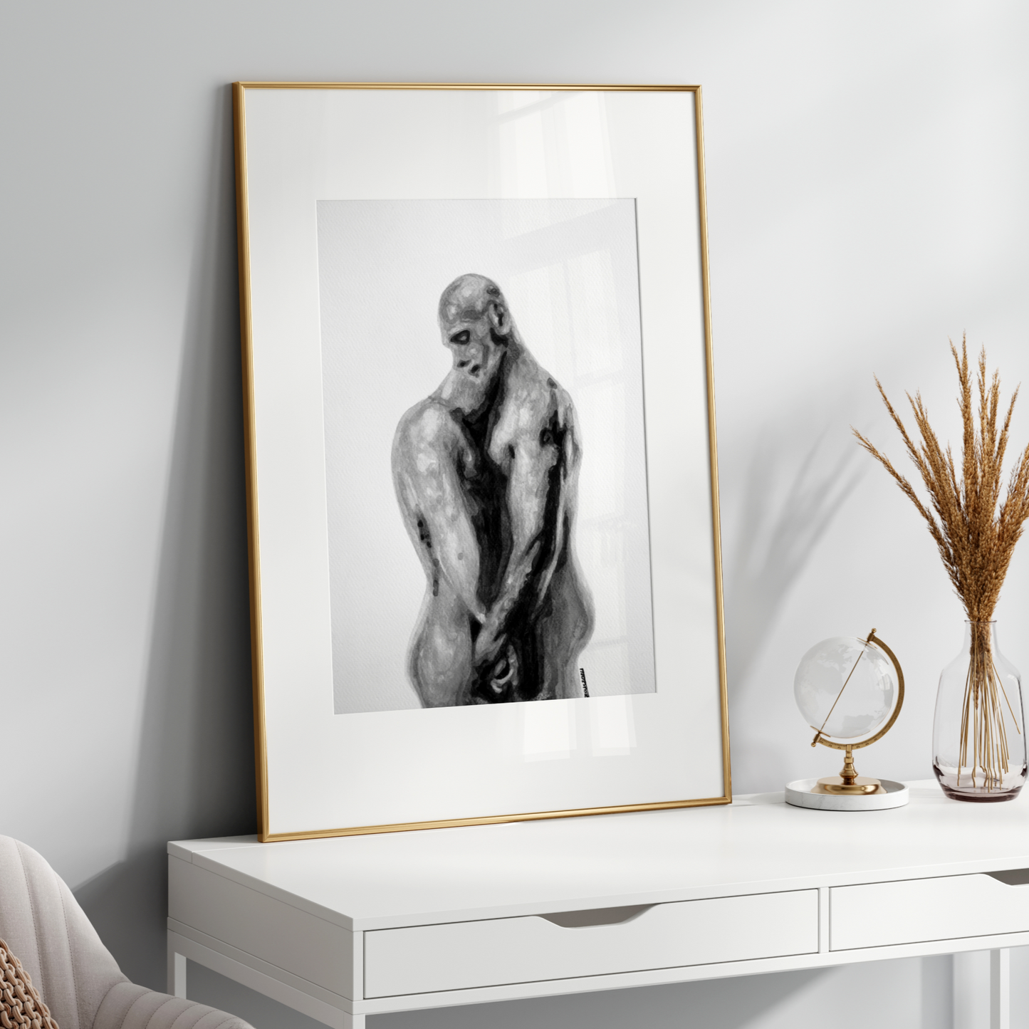Framed black and white artwork of a nude figure on a white console table with decorative items.