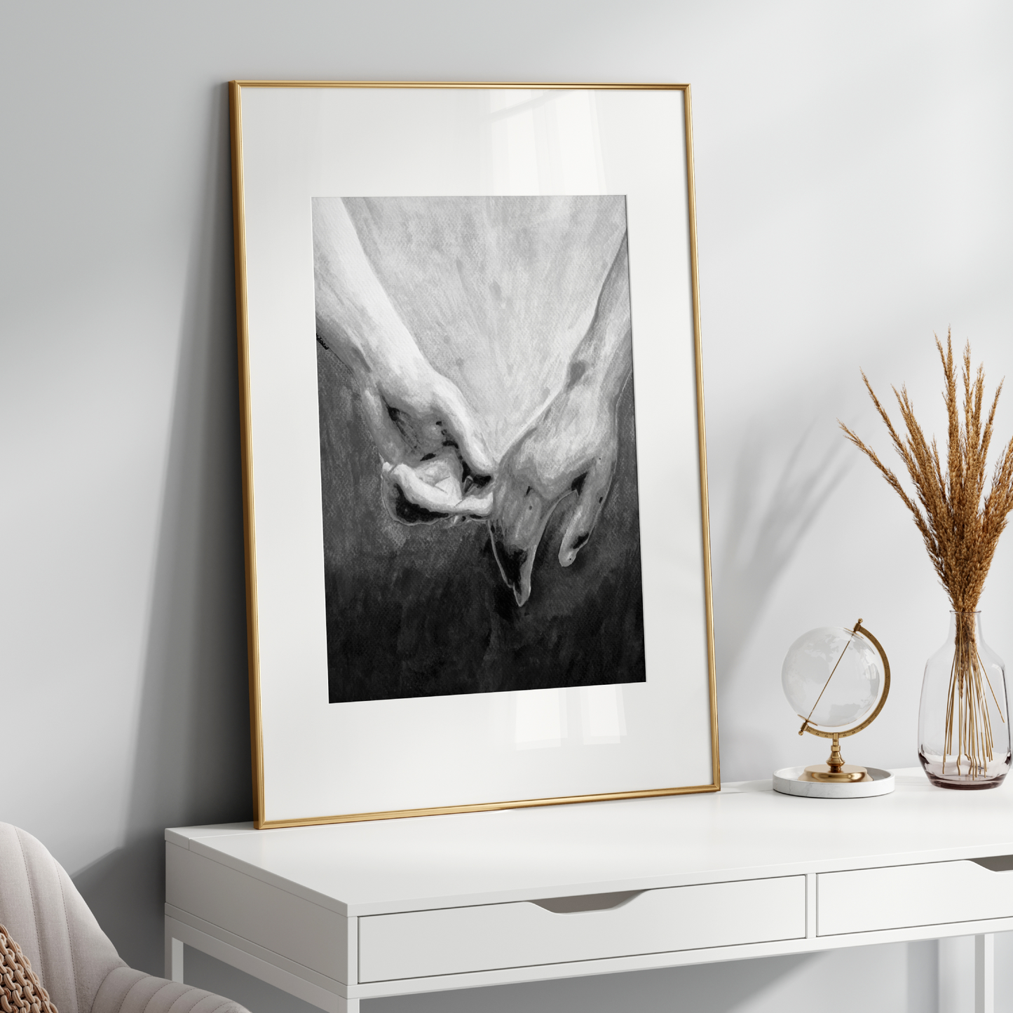 Framed black and white artwork on a white wall above a white console table with decorative items.