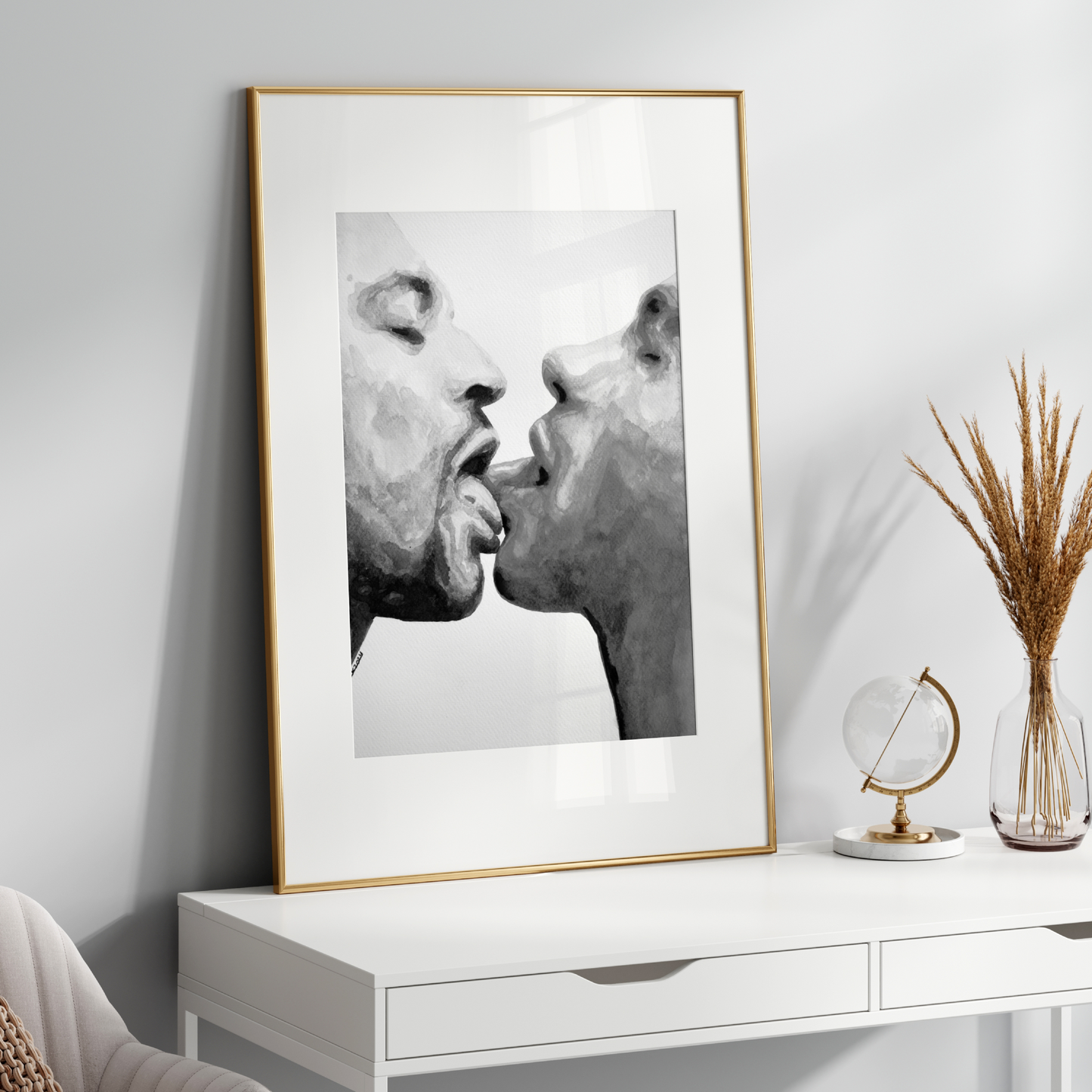 Framed black and white artwork of two faces kissing on a white wall above a white console table.