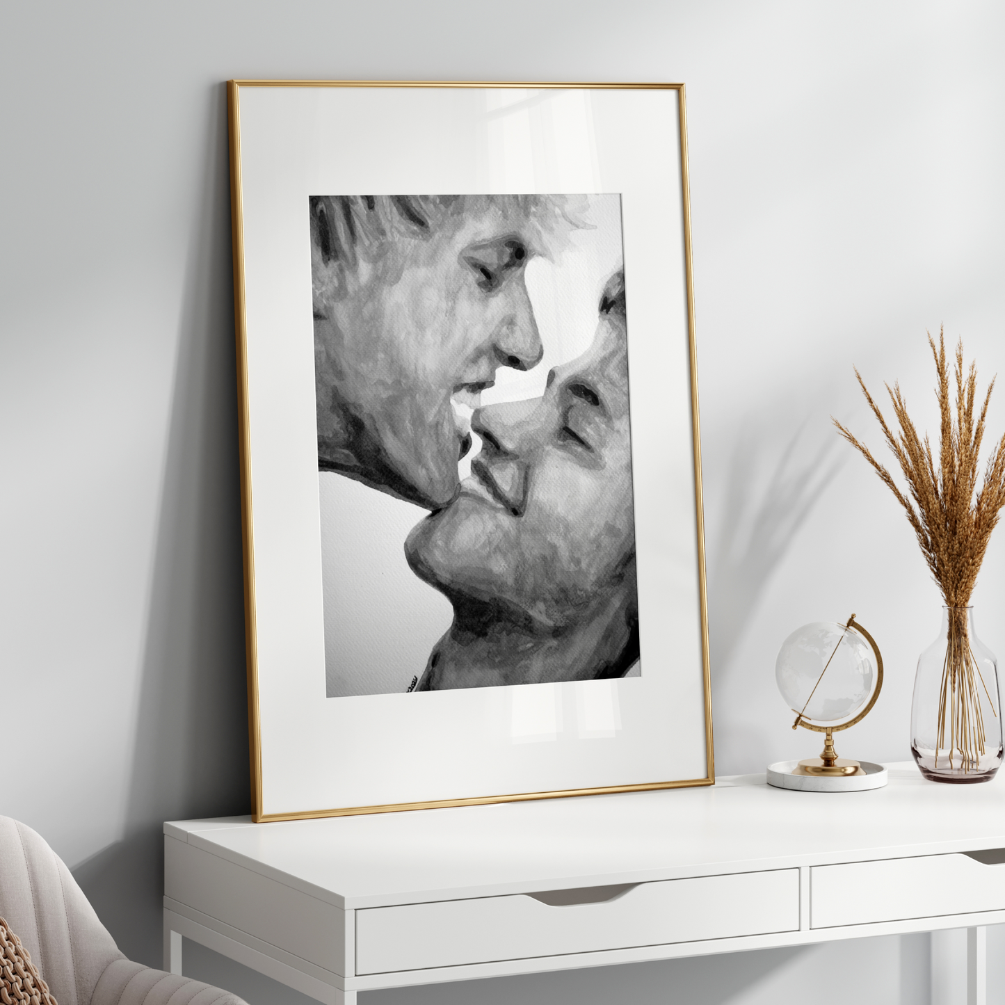 Framed black and white artwork of two faces kissing on a white wall above a white console table.