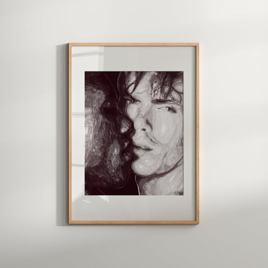 A black and white watercolor art print of a same-sex couple kissing, framed in a light wood frame.