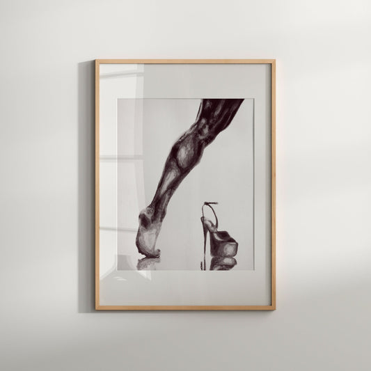 A black and white art print of a male figure in heels, with an abstract and erotic depiction, framed in a simple wood frame.