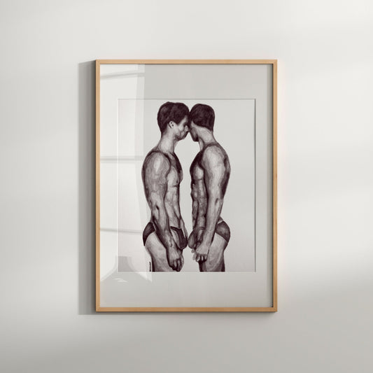 A black and white print of a nude male couple, framed in a light wood frame.