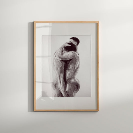 A black and white art print of a same-sex couple in an intimate embrace, framed in a light wood frame.