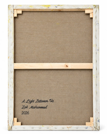 The back of a framed canvas print showing the wooden stretcher bars and corner supports, with the text 'A Light Between Us, Zak Mohammed 2026' printed on the brown linen backing.