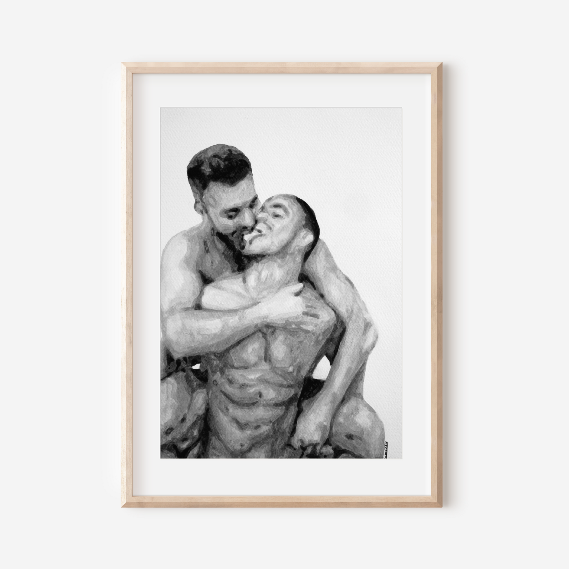 Framed black and white photograph of two people embracing on a white wall.