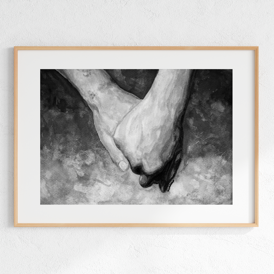 Framed black and white photograph of two hands holding each other on a textured surface.