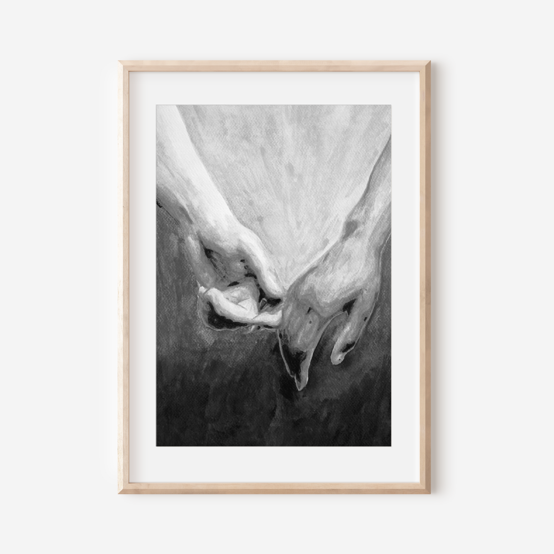 Framed black and white artwork of two hands holding each other on a white wall.