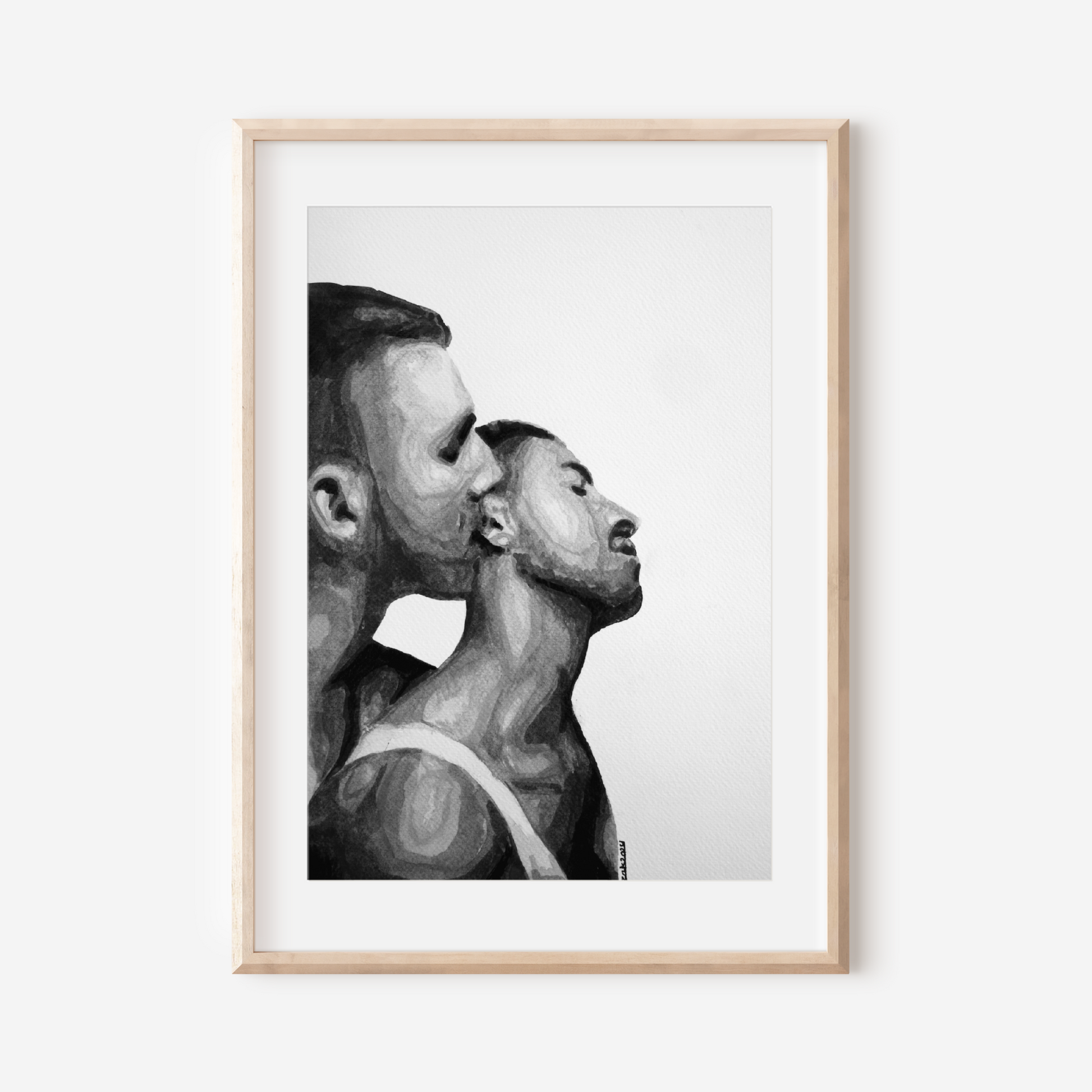 Framed black and white artwork of two men in a close embrace on a white wall.
