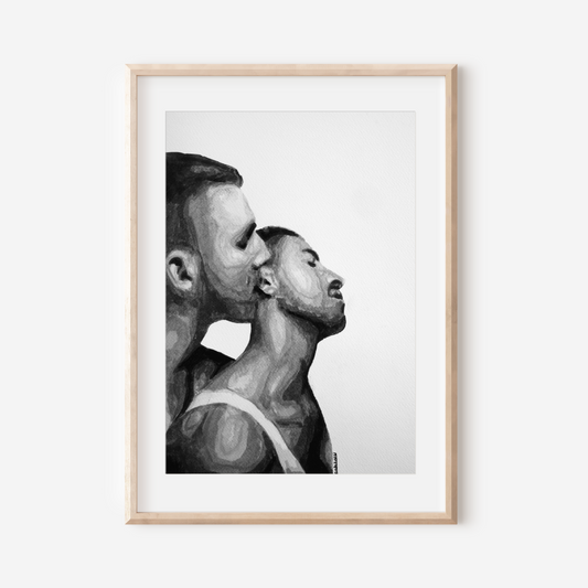Framed black and white artwork of two men in a close embrace on a white wall.
