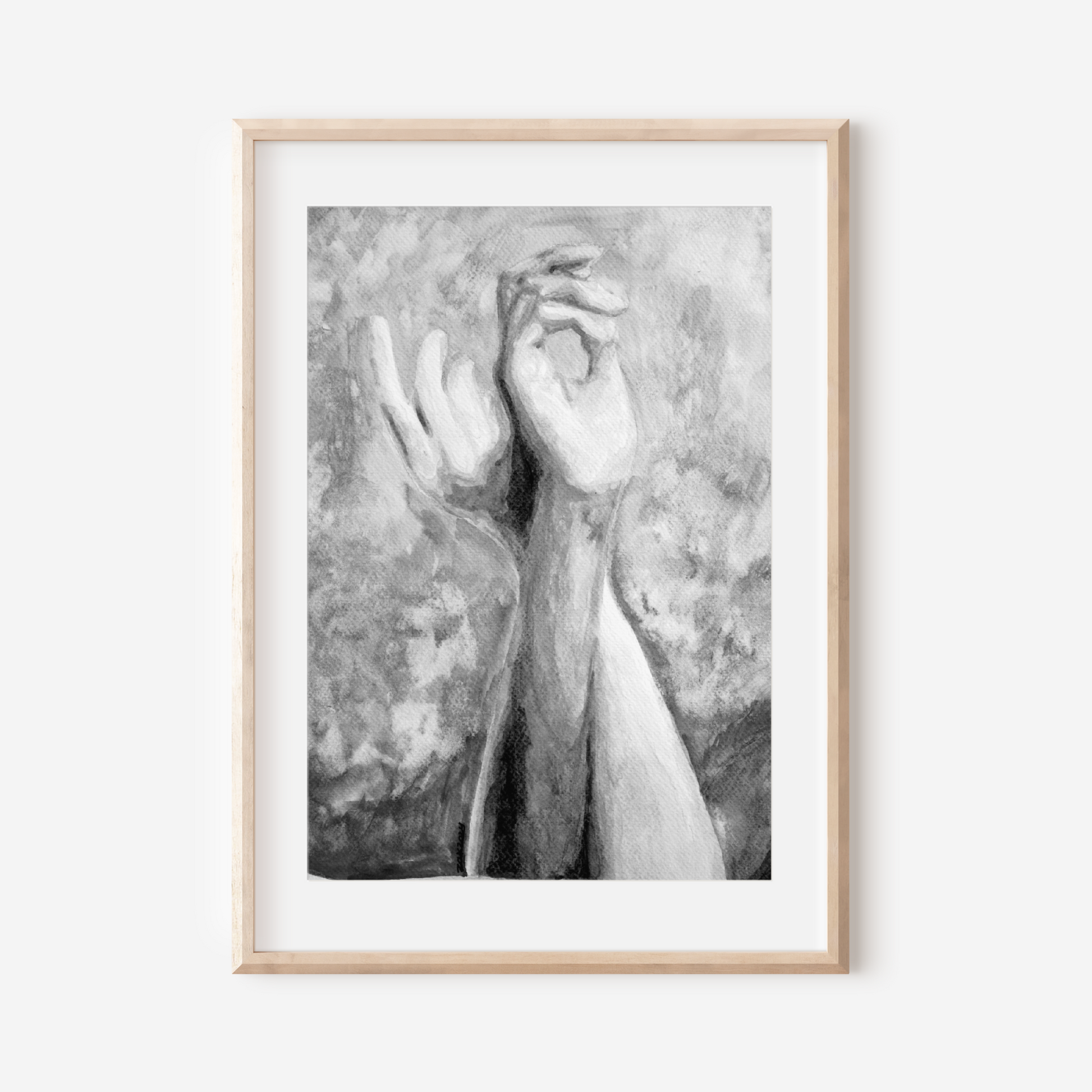 Framed black and white artwork of hands on a white wall