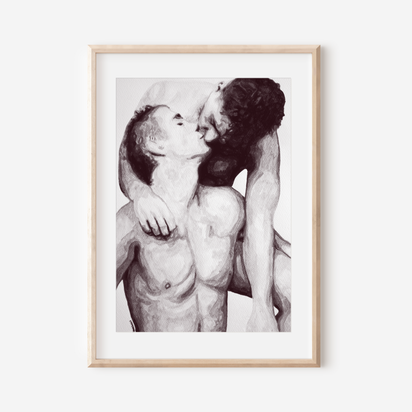 Framed black and white artwork of two nude figures embracing on a white wall.