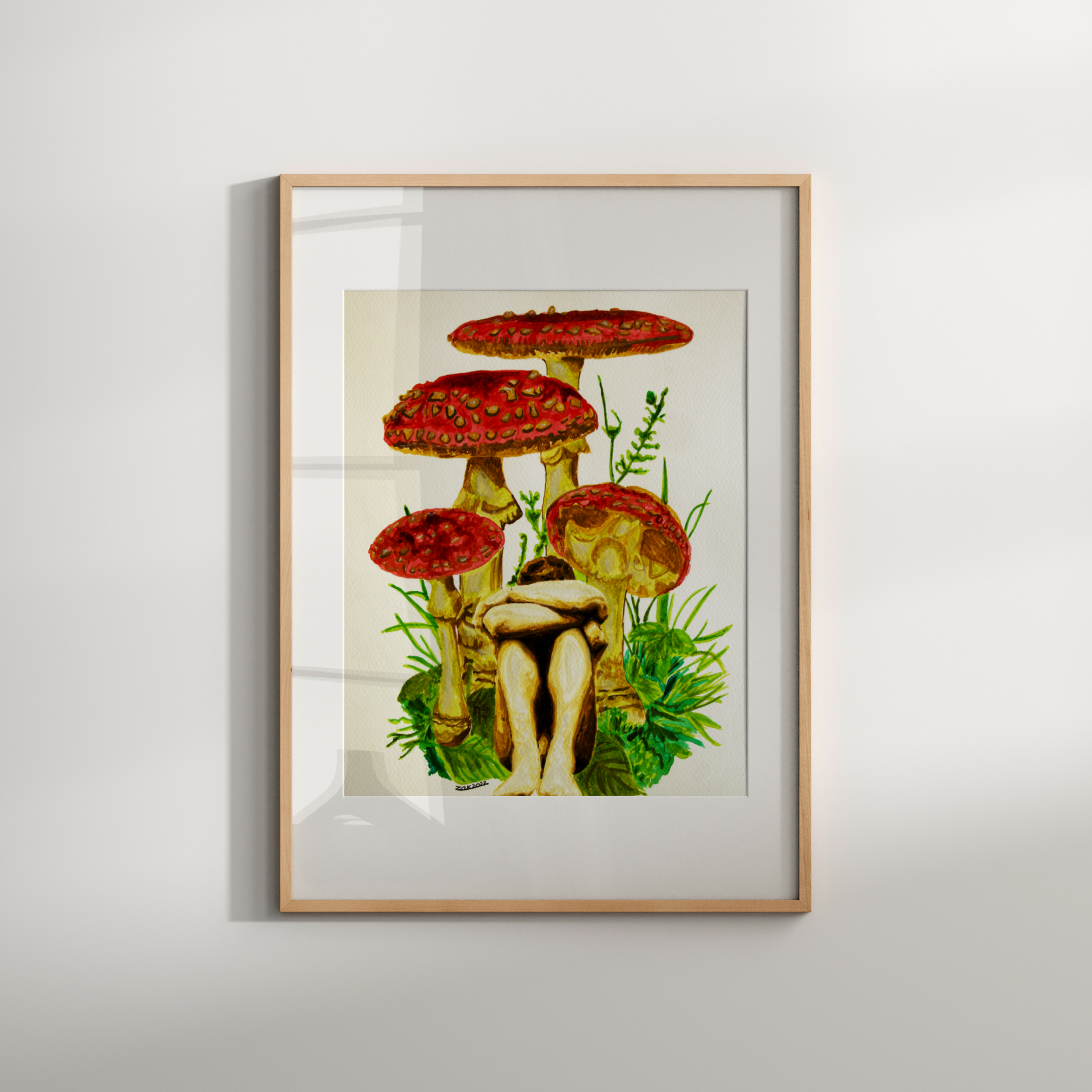 Framed artwork of a woman sitting among red mushrooms on a white wall.