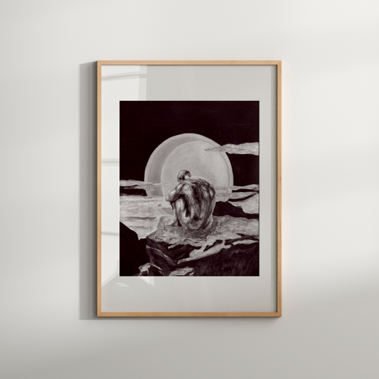 Framed black and white artwork of a person sitting on a rock with a bowl, on a light gray wall.