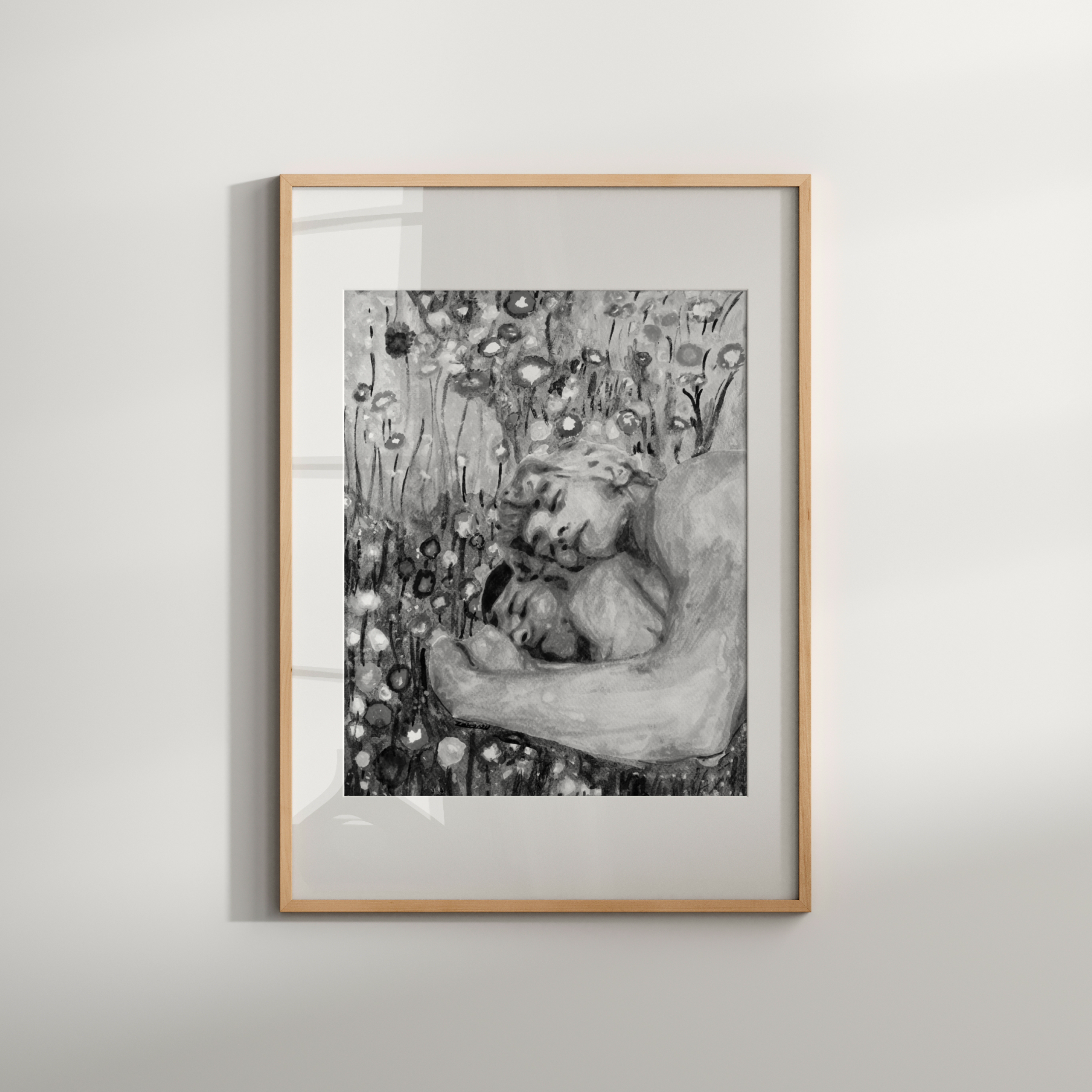 Framed black and white artwork of a woman embracing a child against a floral background on a light gray wall.