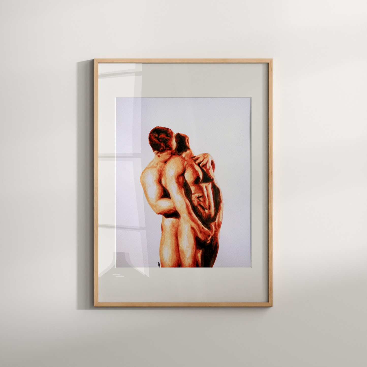Framed artwork of two nude figures embracing on a white wall