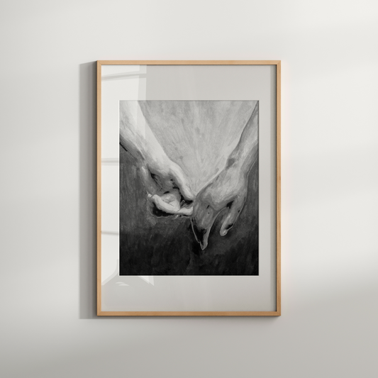 Framed black and white photograph of two hands holding each other on a light gray wall.