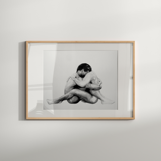 Framed black and white photograph of two people embracing on a light gray wall.