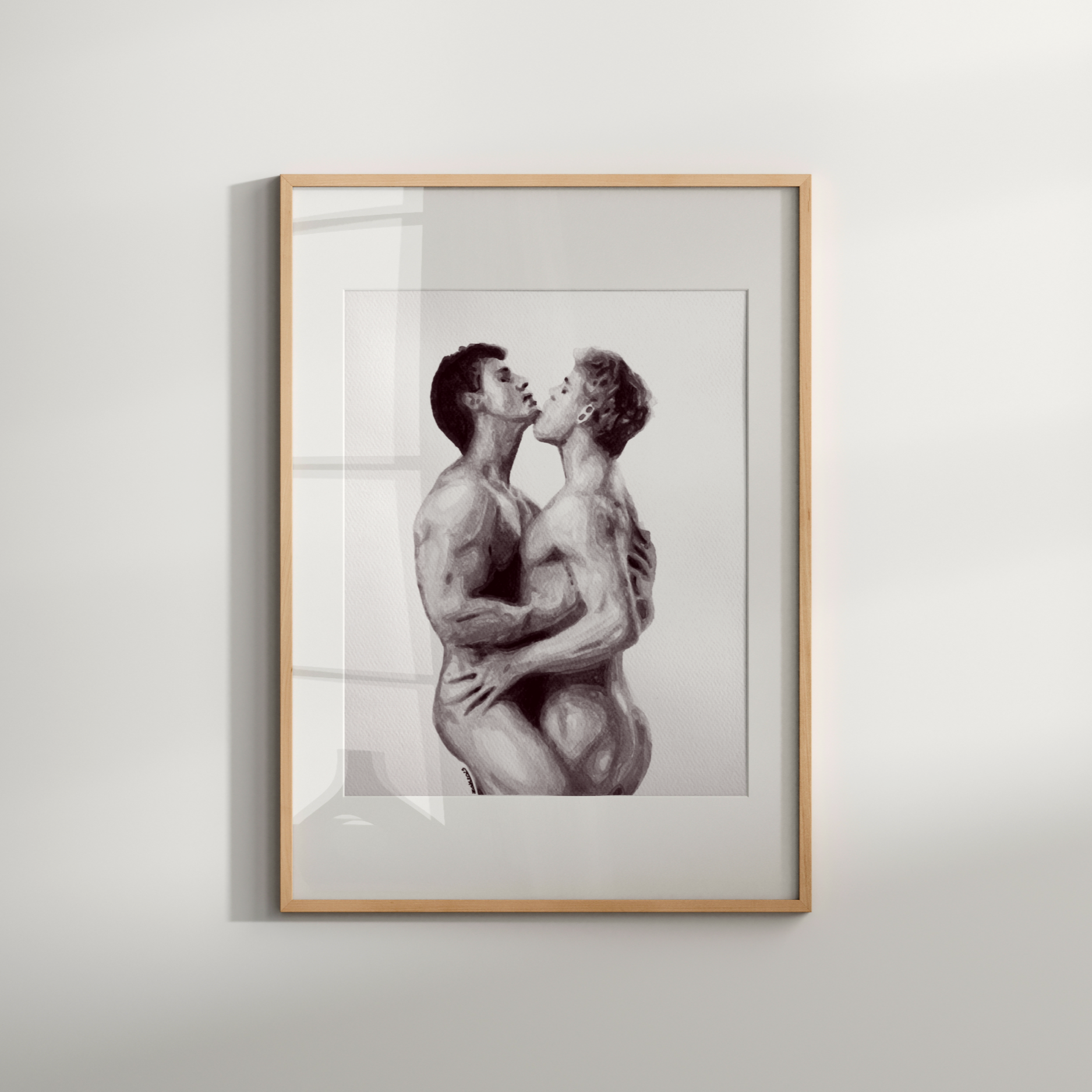 Framed artwork of two nude figures embracing on a white wall.