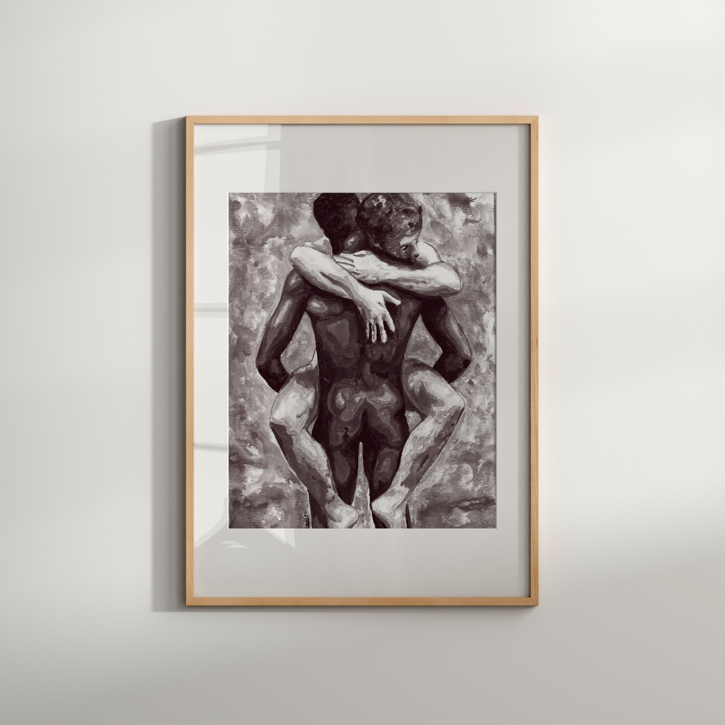 Framed black and white artwork of two nude figures embracing on a light gray background